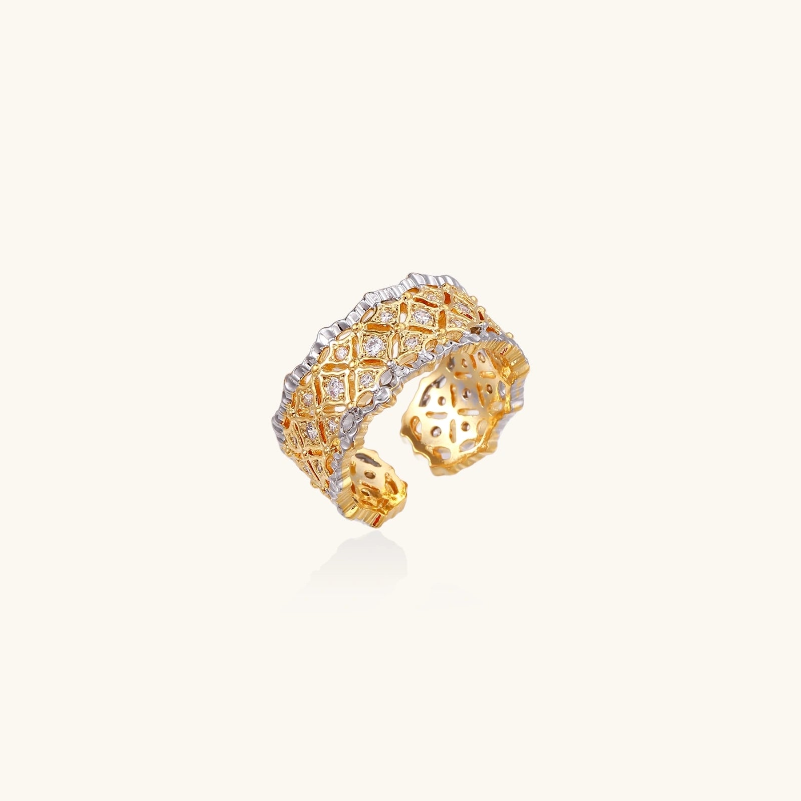 Two-tone ring with geometric lattice pattern in gold and silver finish with crystal accents on beige background