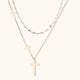 Three-layered gold necklace set with graduated cross pendants in mixed chain styles on white background.