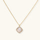 Gold quatrefoil pendant with crystal center on iridescent mother-of-pearl base, adjustable gold chain on cream background